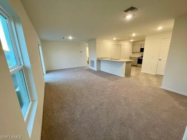 Unfurnished living room featuring light colored carpet and recessed lighting