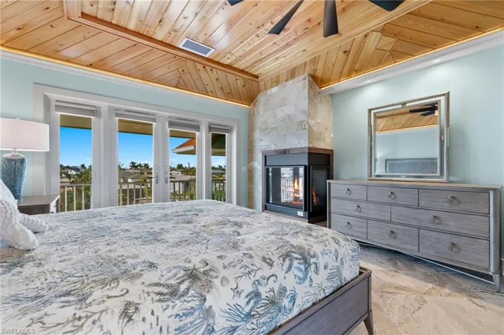 The spacious ensuite primary bedroom features a gas fireplace and walk-in closet. It opens to a balconyoverlooking the waterfront and pool and spa area.