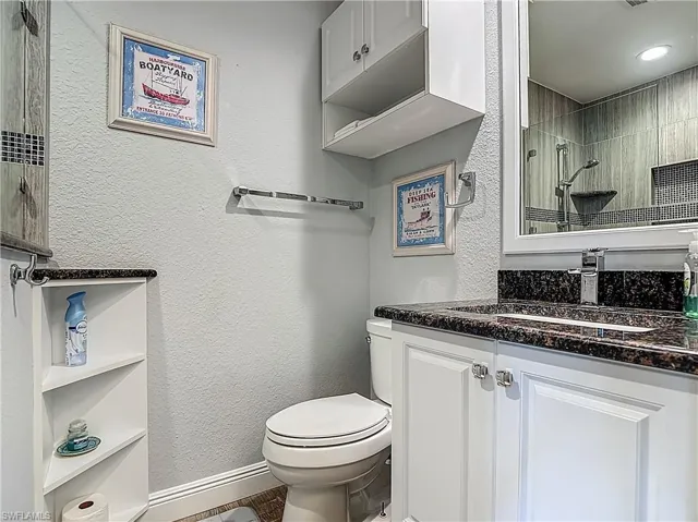 Bathroom with vanity, a textured wall, and tiled shower
