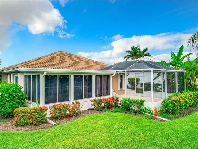 Back of property featuring a lanai, a tile roof, a yard, and a sunroom