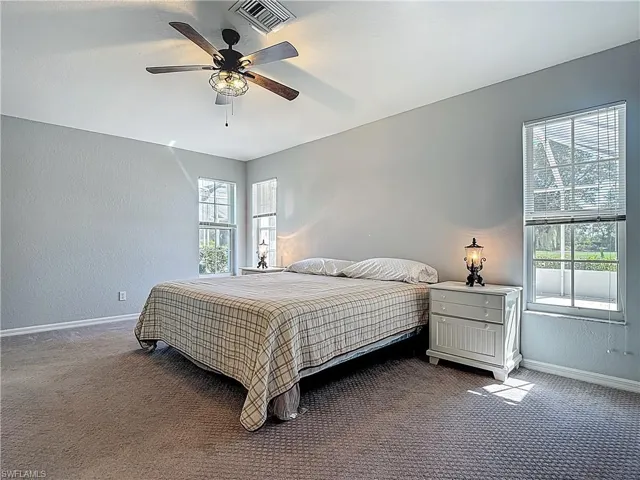 Bedroom featuring a textured wall, ceiling fan, and dark colored carpet