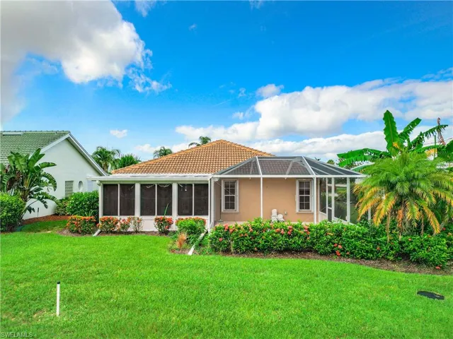 Back of property with a sunroom, a yard, a lanai, and stucco siding
