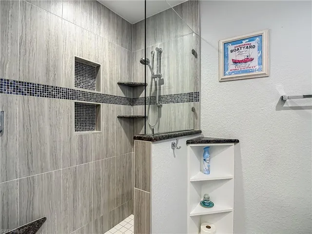Bathroom with a walk in shower and a textured wall