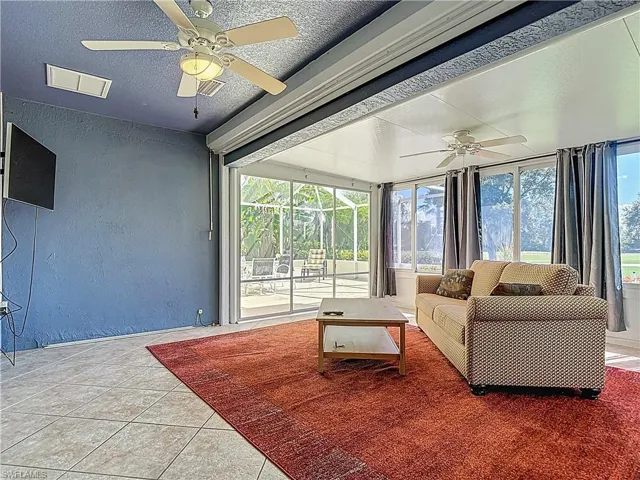 Sunroom / solarium featuring a textured wall, a textured ceiling, and tile patterned floors