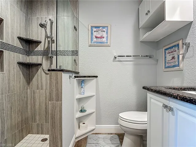 Bathroom featuring vanity, a stall shower, and a textured wall