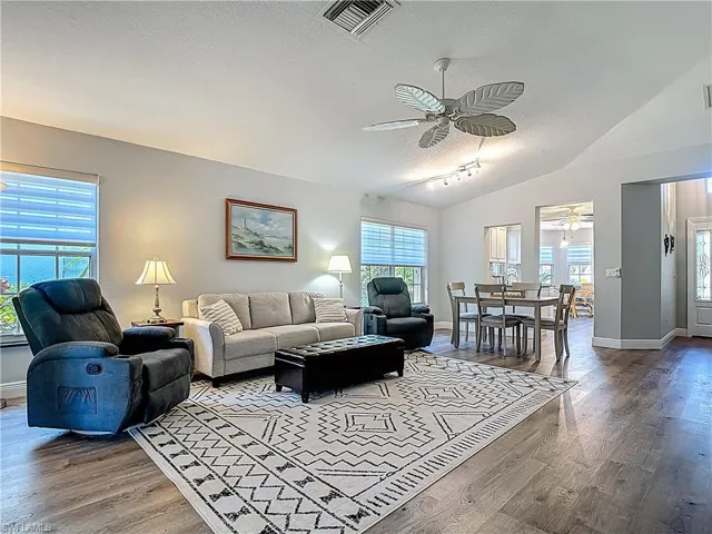 Living area featuring ceiling fan, healthy amount of natural light, wood finished floors, and rail lighting