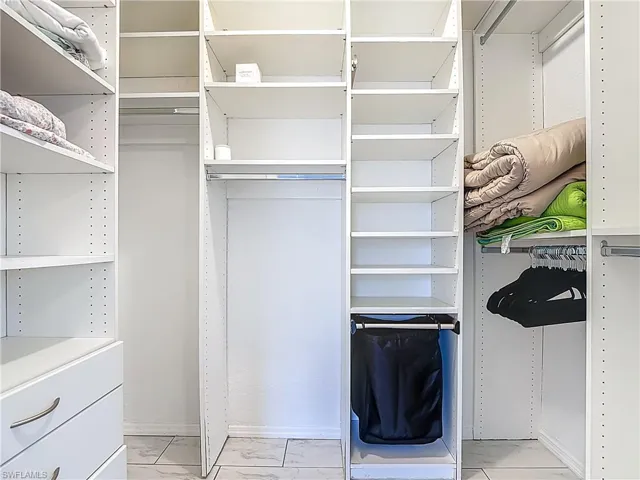 Walk in closet with light marble finish flooring