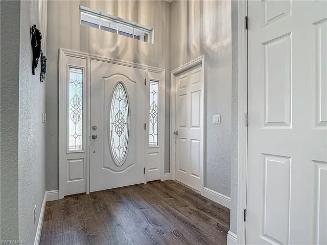 Foyer with a textured wall and dark wood-style floors