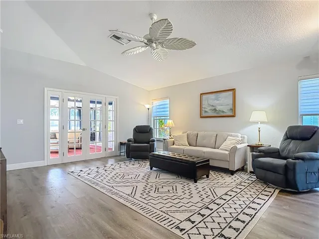Living room featuring french doors, vaulted ceiling, light wood-style flooring, and ceiling fan