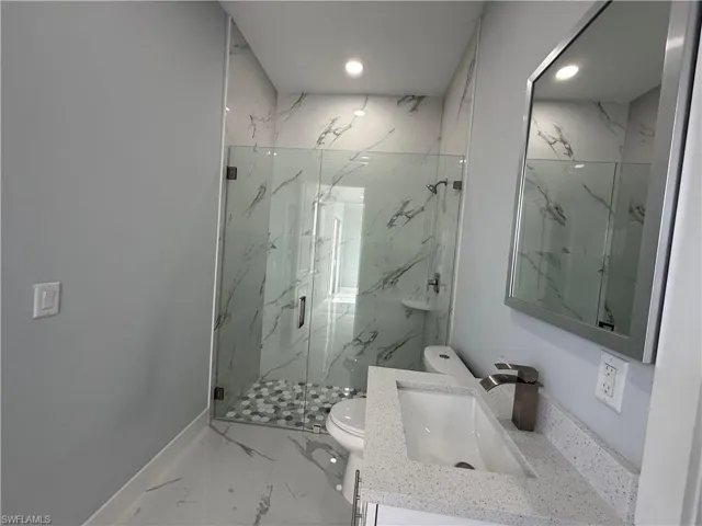 Bathroom featuring vanity, marble finish floors, a marble finish shower, and recessed lighting