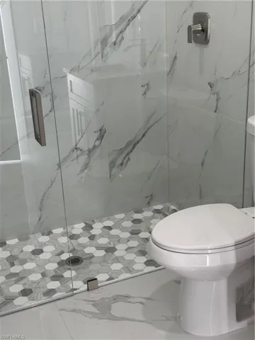 Full bath with a marble finish shower and marble finish flooring