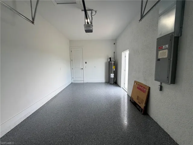Garage featuring electric panel, water heater, and a garage door opener