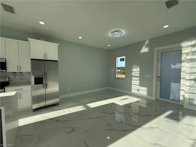 Kitchen with stainless steel appliances, white cabinets, light stone countertops, and recessed lighting