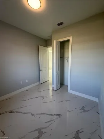 Unfurnished bedroom featuring a closet and light marble finish flooring