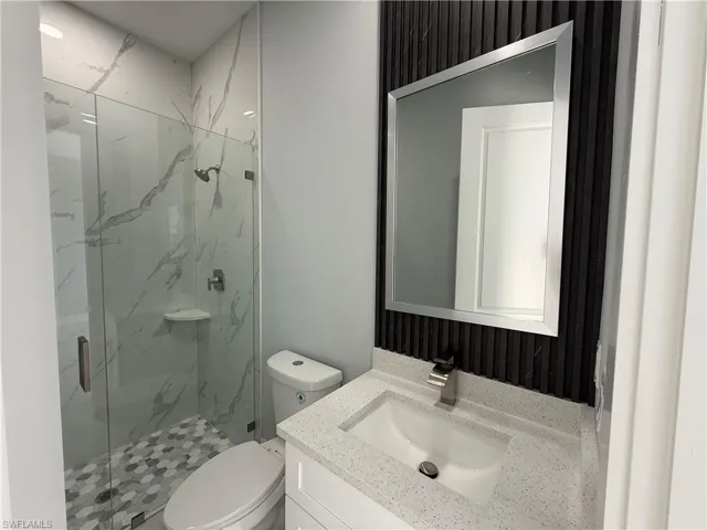 Bathroom featuring vanity and a marble finish shower