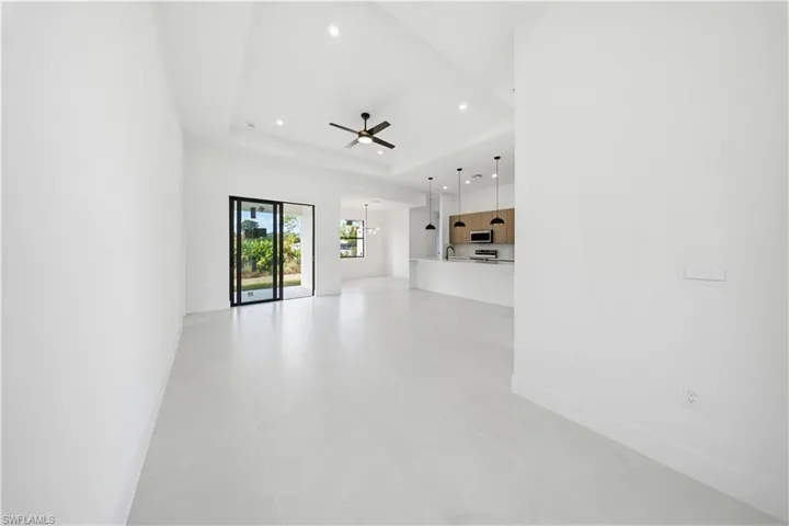 Unfurnished living room with a ceiling fan, a raised ceiling, and a chandelier