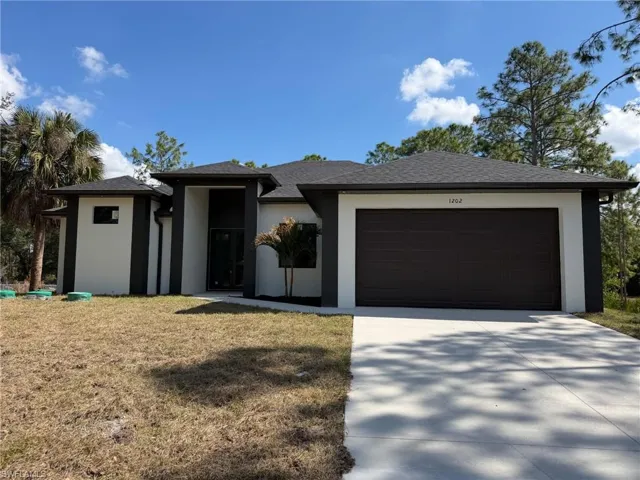Prairie-style home featuring concrete driveway, a front lawn, a garage, and stucco siding