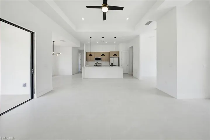 Unfurnished living room featuring ceiling fan, a high ceiling, and a chandelier
