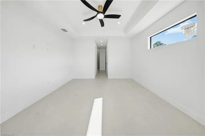 Unfurnished bedroom featuring a tray ceiling, recessed lighting, and ceiling fan