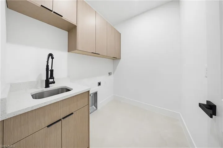Laundry area with electric dryer hookup, cabinet space, light tile patterned floors, and hookup for a washing machine