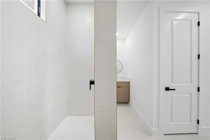 Bathroom with vanity, light tile patterned flooring, a tile shower, and recessed lighting
