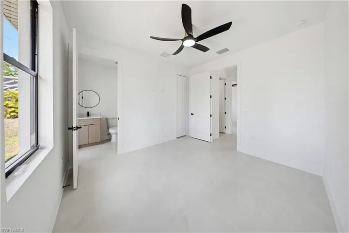 Unfurnished bedroom with a ceiling fan and connected bathroom