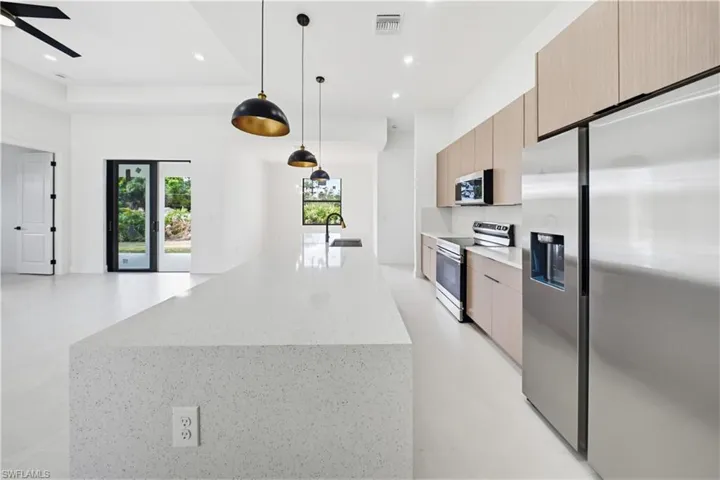Kitchen featuring stainless steel appliances, pendant lighting, light stone counters, a large island, and modern cabinets