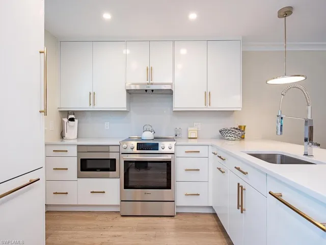 Kitchen with stainless steel appliances, white cabinetry, tasteful backsplash, pendant lighting, and crown molding