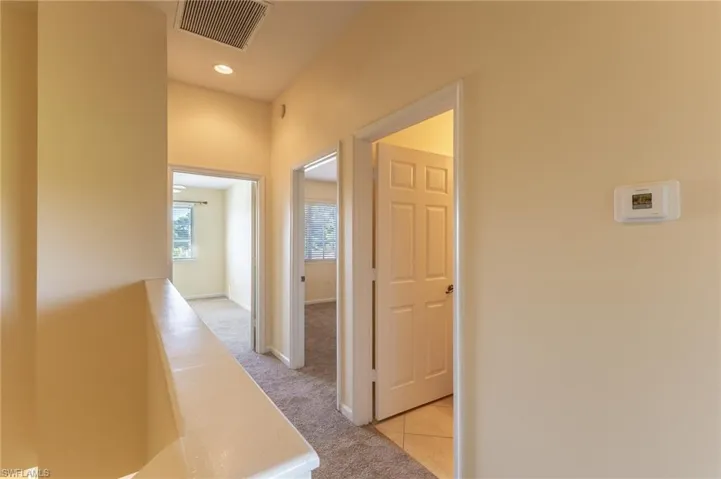 Hall with an upstairs landing, light carpet, and light tile patterned floors