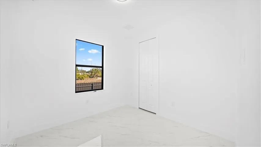 Unfurnished bedroom featuring light marble finish floors and a closet