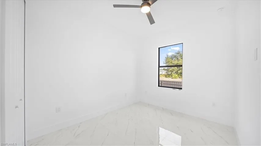 Spare room featuring marble look tiles and a ceiling fan
