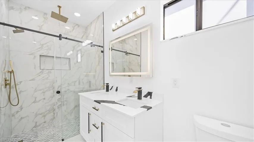 Full bath featuring double vanity and a marble finish shower