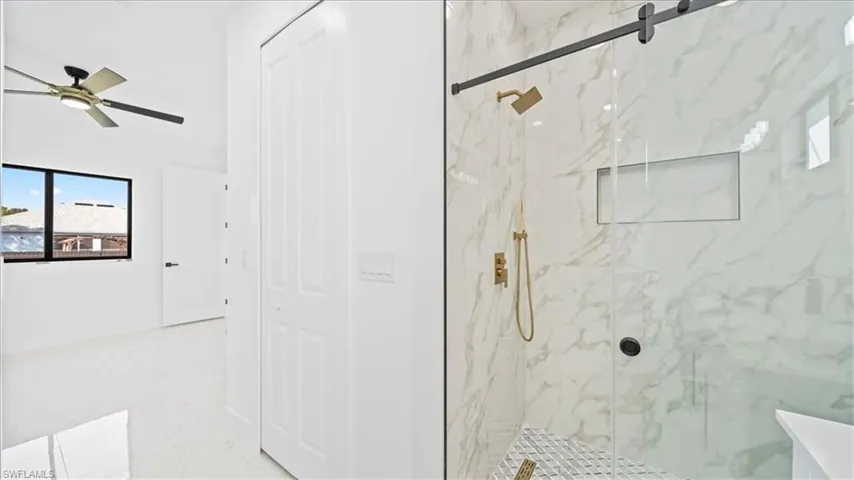 Bathroom with a marble finish shower, ceiling fan, and a closet