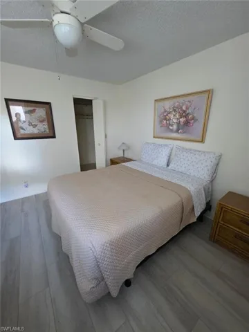 Bedroom with a textured ceiling, wood finished floors, ceiling fan, and a closet