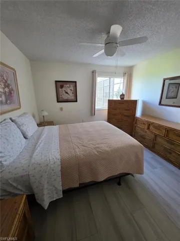 Bedroom with wood finished floors, a textured ceiling, and a ceiling fan