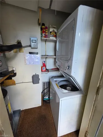 Washroom with stacked washer and clothes dryer and water heater