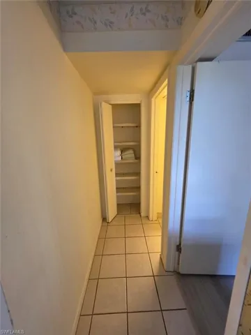 Hallway featuring light tile patterned floors and baseboards