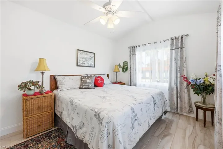 Another view of a Guest Bedroom featuring vaulted ceiling with beams, a ceiling fan, and light tile floors