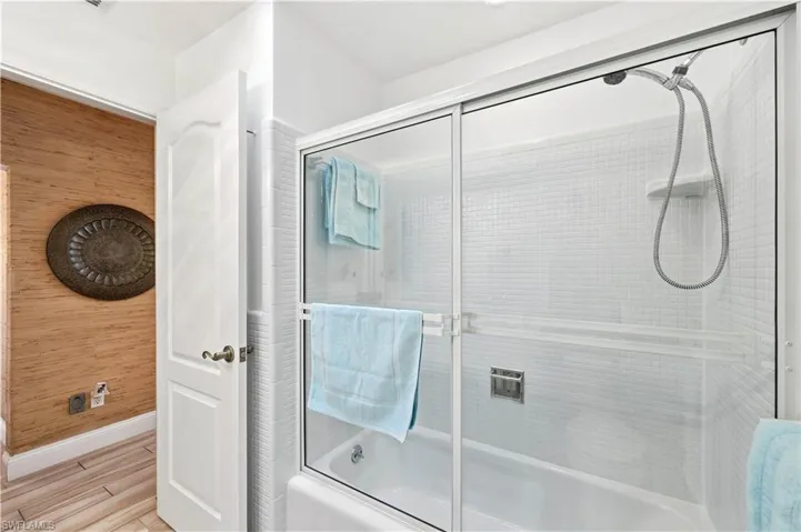 Guest Bathroom with combined bath / shower with glass door and tiled floors