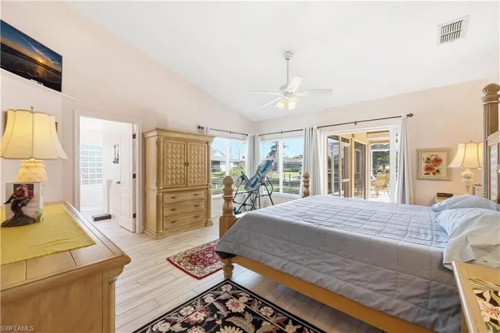 Master Bedroom Suite with lofted ceiling, light tile floors, access to the lanai and pool, a ceiling fan, and connected bathroom