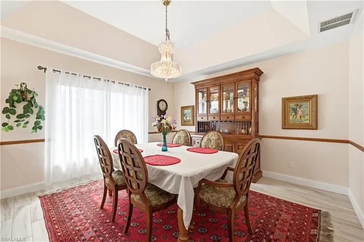 Dining area with hanging lights, tile floors, and a tray ceiling.