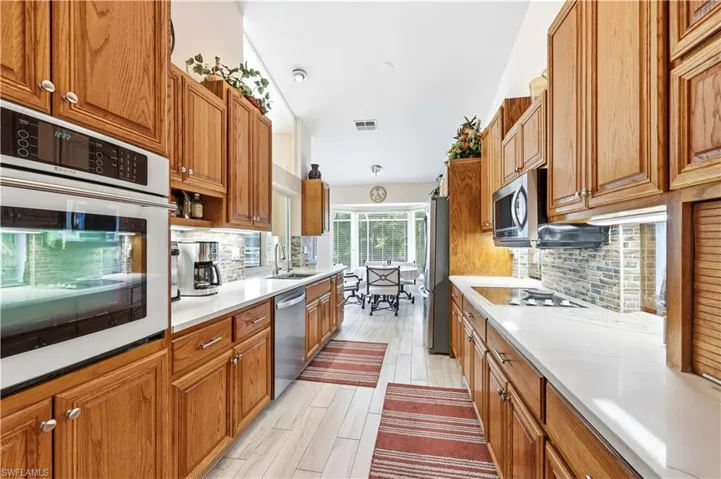 Kitchen featuring solid wood cabinets, stainless steel appliances, tile floors, and decorative backsplash.