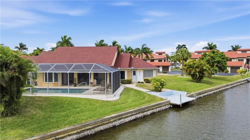 Back of property with a lawn, a water view, screen enclosure, and a saltwater pool
