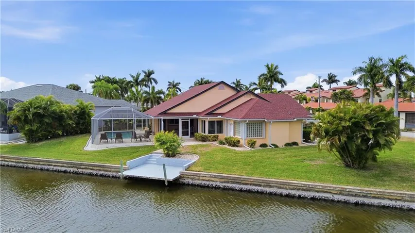 Back of property with a water view, a screened enclosure and a saltwater heated swimming pool