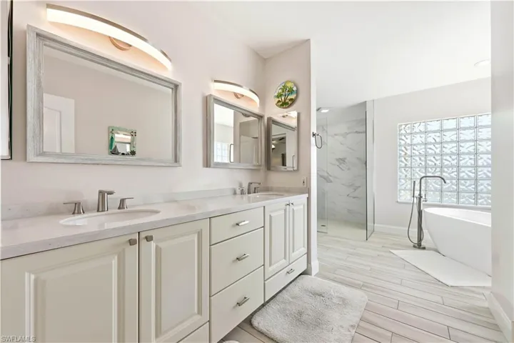 Master Bathroom featuring double vanity, a marble finish shower, a soaking tub, and tile floors and walk-in closet.