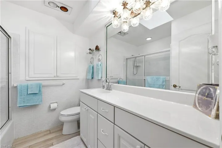 Full Guest bathroom with vanity and combined bath / shower with door enclosure.