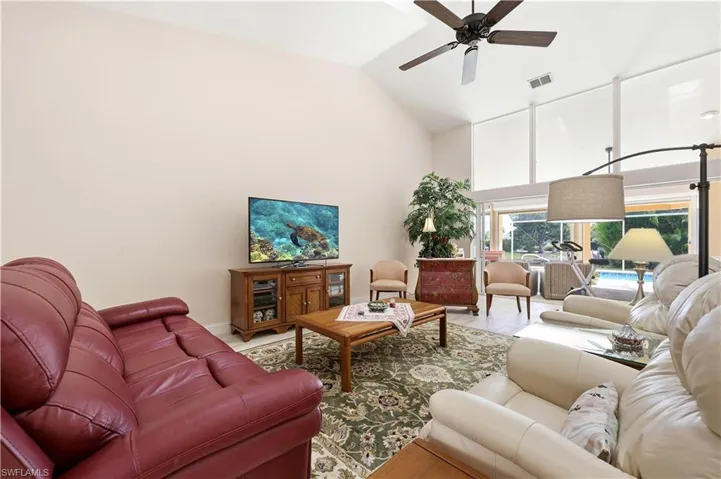 Living room featuring a ceiling fan and vaulted ceiling, tile floor.