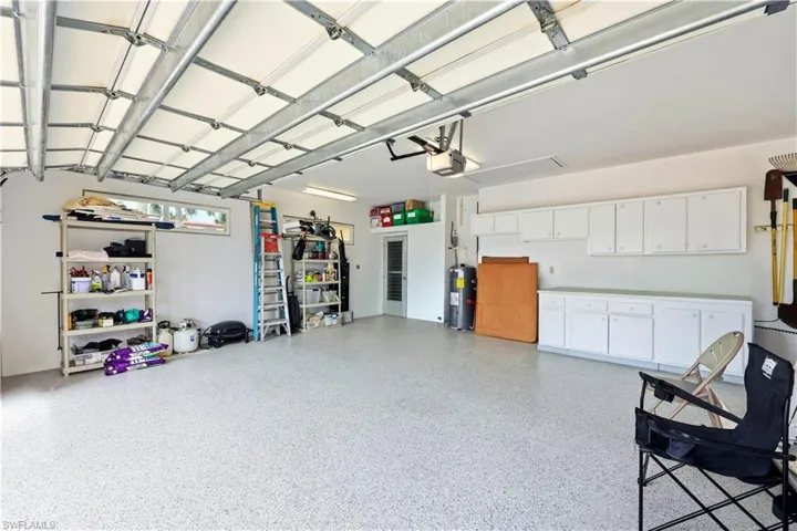 Oversized Garage featuring Garage Door Opener, a electric water heater and Epoxy Floor, Cabinets and a 18' Garage Door. Two Side Entrance Doors to the yard.