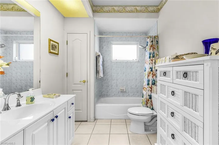 Full bathroom featuring vanity, shower / tub combo with curtain, and light tile patterned flooring