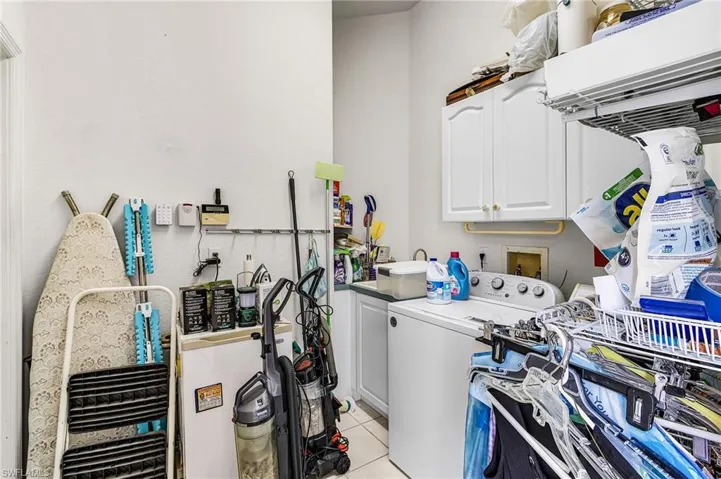 Laundry room with cabinet space, light tile patterned floors, and washer and dryer